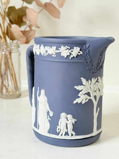 Vintage Wedgwood Portland blue Jasperware jug decorated with white neoclassical figures and a grapevine border, styled with dried stems.
