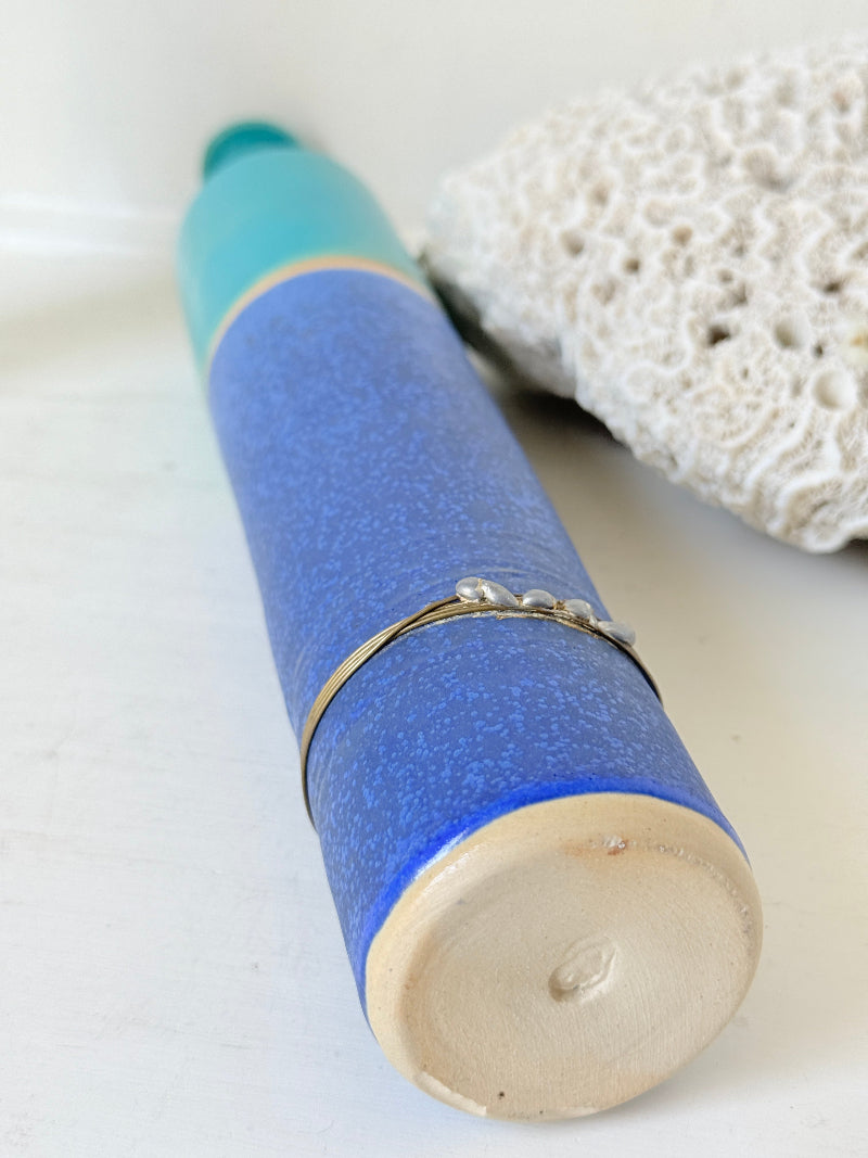 Tall vintage studio pottery bottle vase in turquoise and cobalt blue glaze, photographed on a white surface