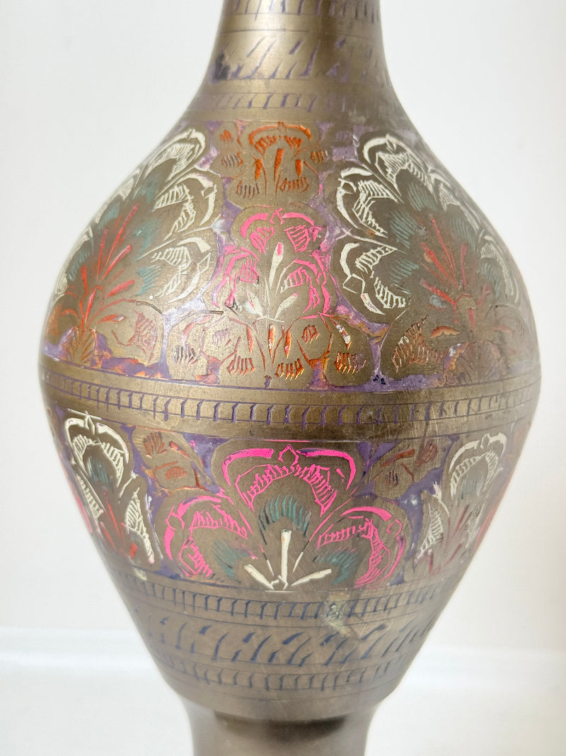Vintage Indian engraved brass vase with enamel floral decoration and aged patina styled with dried stems on white surface