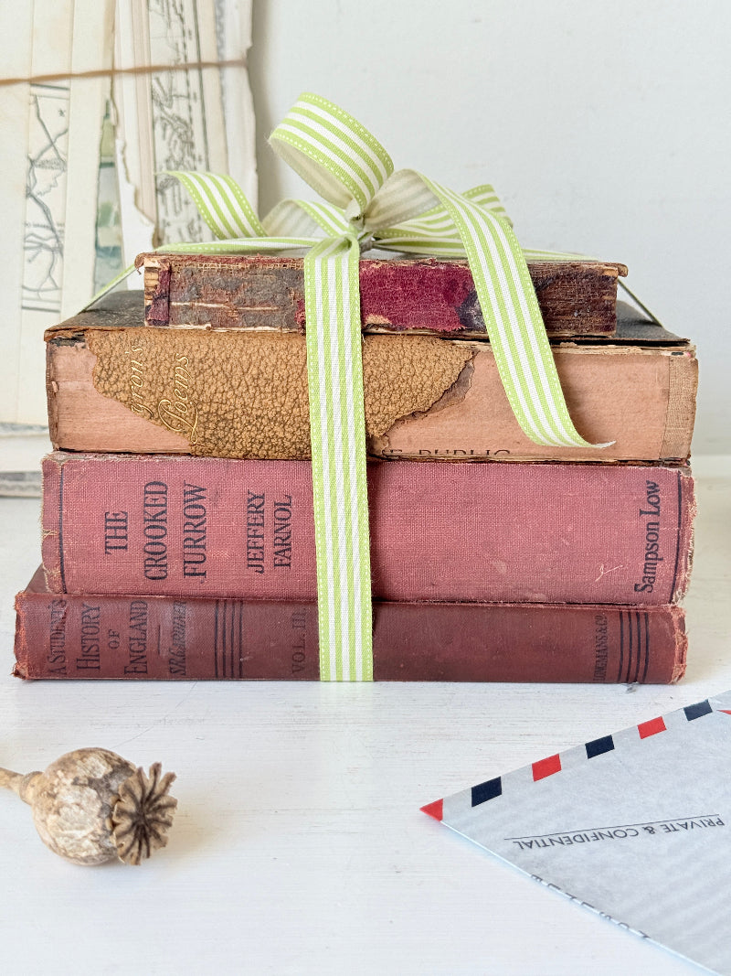 Vintage decorative book bundle with red burgundy cream and green hardback covers tied with green stripe ribbon for interior styling