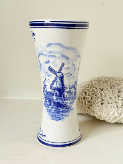 Blue and white Delft hand painted ceramic vase with windmill and floral decoration, photographed on white surface.