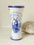 Blue and white Delft hand painted ceramic vase with windmill and floral decoration, photographed on white surface.