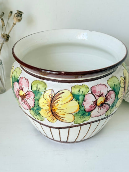 Large European hand painted floral ceramic jardinière with yellow, pink and green flowers on a white base, styled on a white surface with dried foliage.