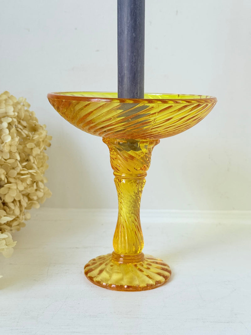 Amber pressed glass candle holder or compote with swirl design and pedestal base, photographed on a white background