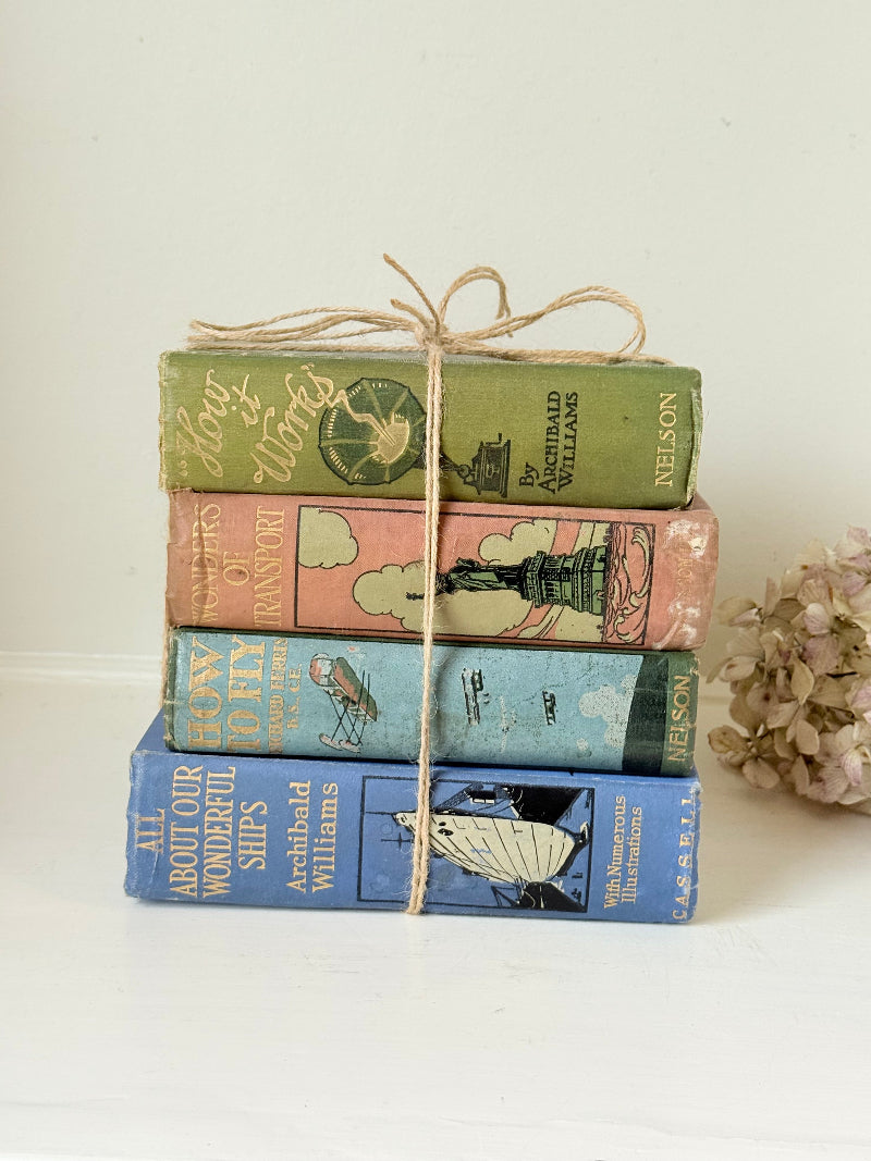 Vintage decorative book bundle in green, blue, and coral with printed lettering, tied with twine, photographed on a white surface
