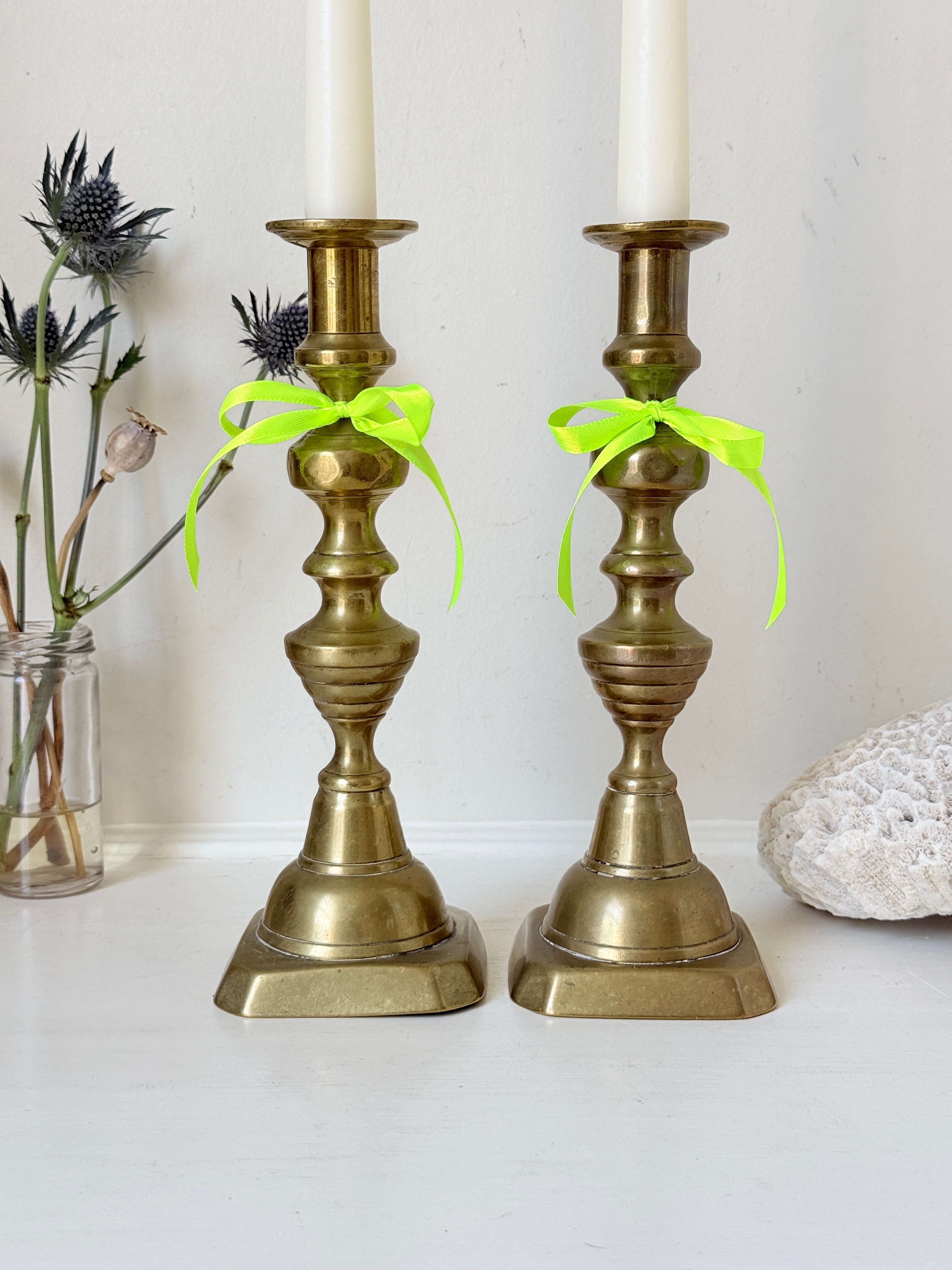 Pair of vintage brass candlesticks with turned stems and square bases, photographed on a white surface