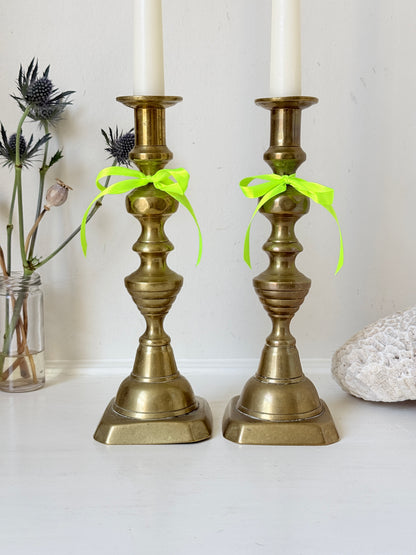 Pair of vintage brass candlesticks with turned stems and square bases, photographed on a white surface