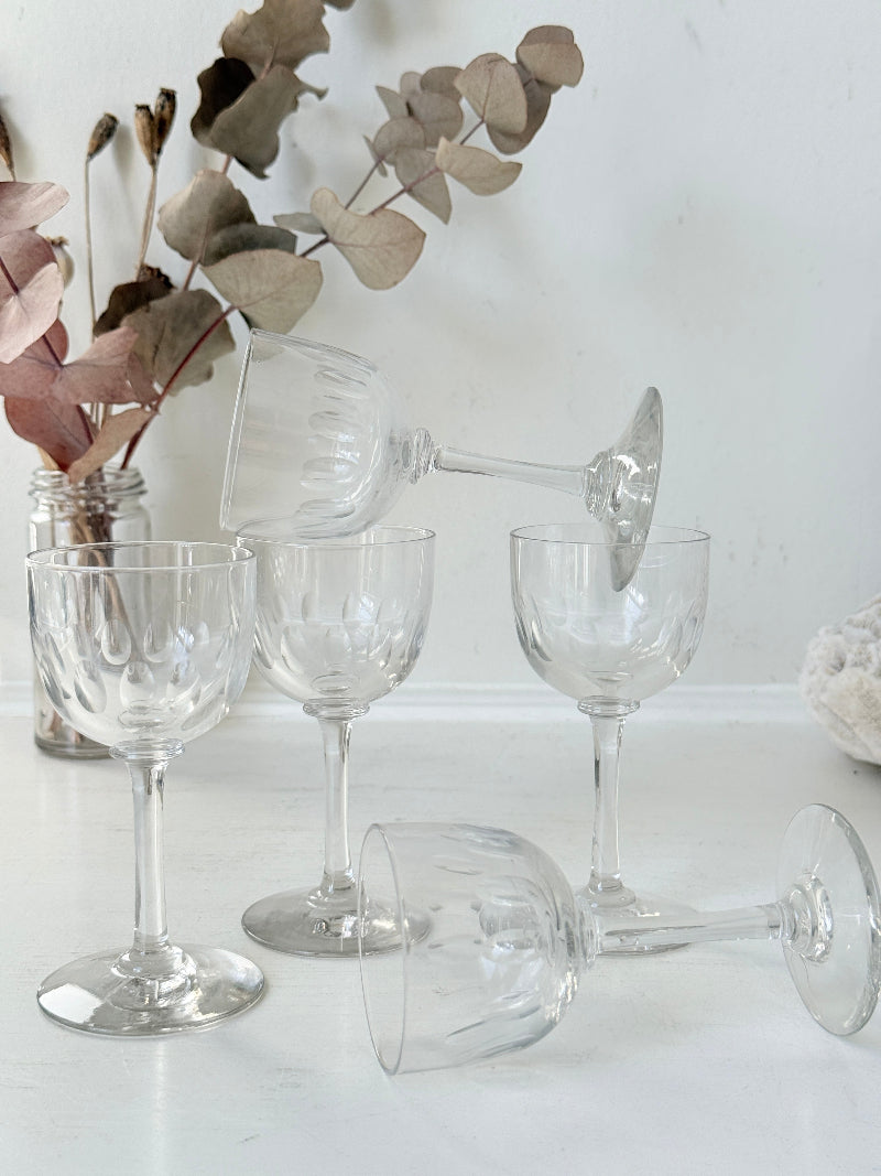 Set of 5 vintage clear glass liqueur glasses with small stems photographed on a white surface