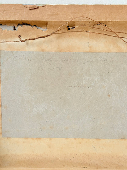 Close-up of the back of a vintage paper card or document, showing a beige central sheet with faint handwritten text, bordered by aged tan paper and a torn brown cardboard edge with loose string.