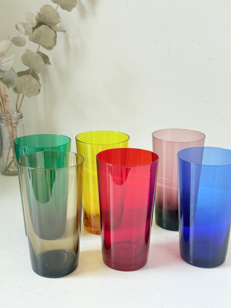 Set of six mid-20th century Boussu coloured glass tumblers in green, yellow, red, violet, blue and brown, photographed on white surface.