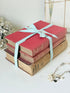 Three antique red books with aged spines tied with a turquoise striped ribbon on a white surface, styled with glass and beads