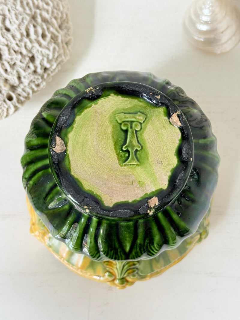 A vintage green glazed ceramic bowl or planter shown from a top-down angle, featuring a dark green outer rim, a lighter green interior, and a central raised monogram letter &
