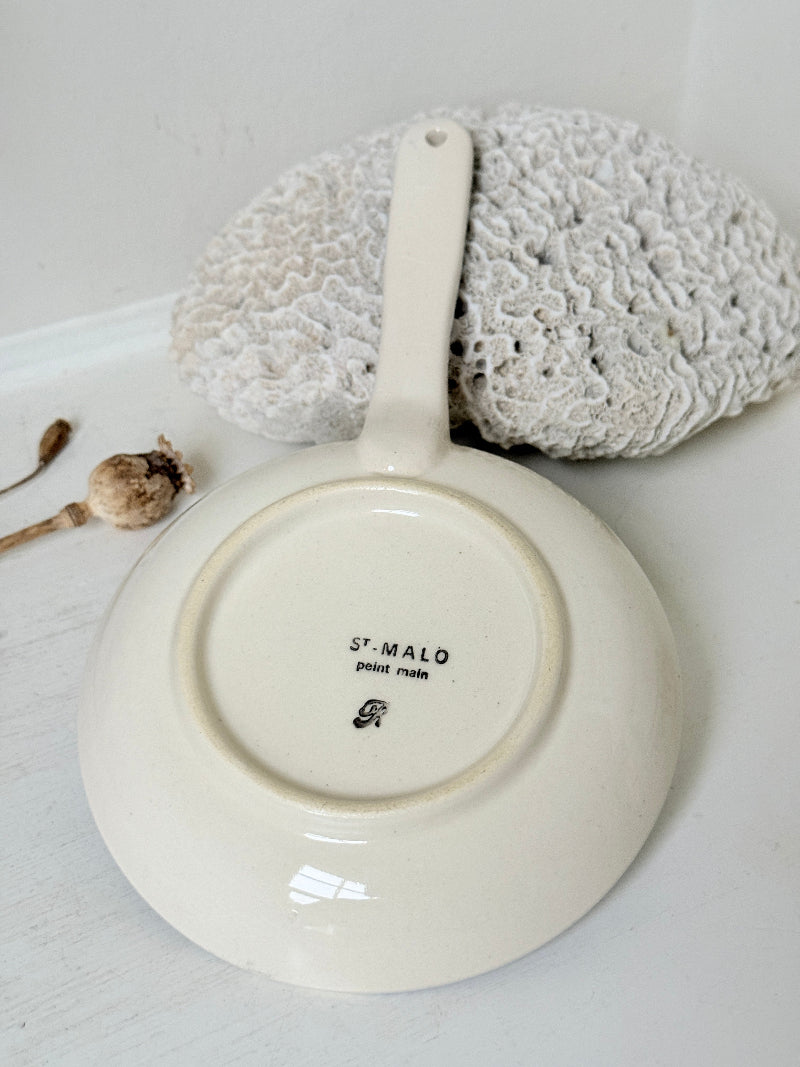 French Quimper faience handled wall dish with Petit Breton figure and blue rim, photographed on a white surface