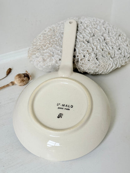 French Quimper faience handled wall dish with Petit Breton figure and blue rim, photographed on a white surface