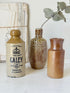 Three antique stoneware bottles, a printed Caley of Norwich and a Portuguese Campos Filhos, photographed on a white surface