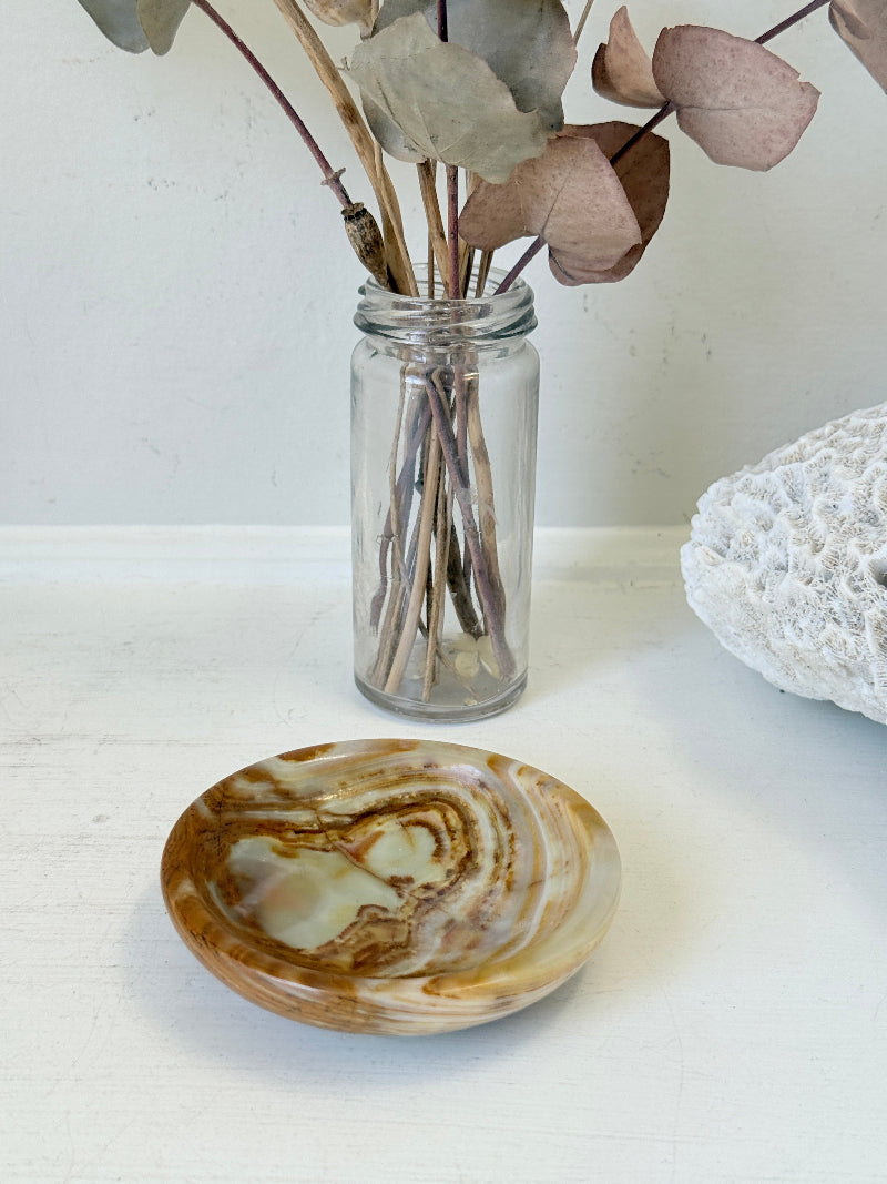 Vintage onyx marble soap dish in honey and cream with banded veining, photographed on a white surface