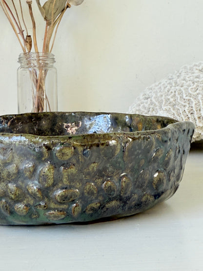 Studio pottery olive bowl with green and charcoal glaze, photographed on a white surface