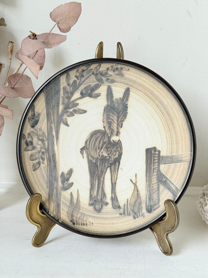 Vintage plate with hand painted brown donkey illustration and dark rim, photographed on a white surface
