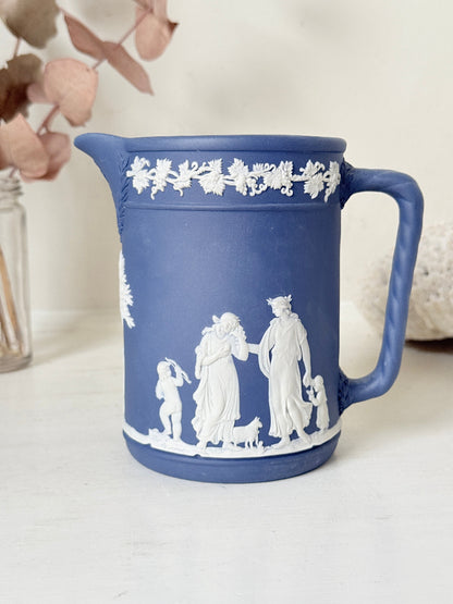 Vintage Wedgwood Portland blue Jasperware jug decorated with white neoclassical figures and a grapevine border, styled with dried stems.