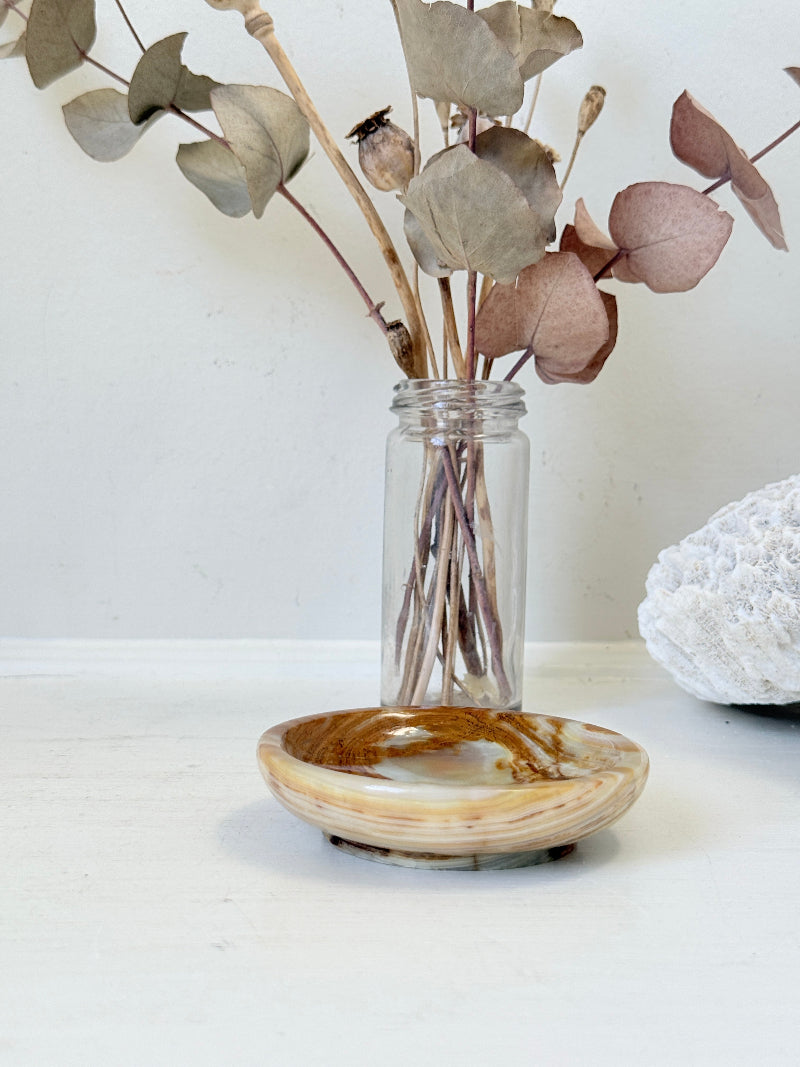 Vintage onyx marble soap dish in honey and cream with banded veining, photographed on a white surface