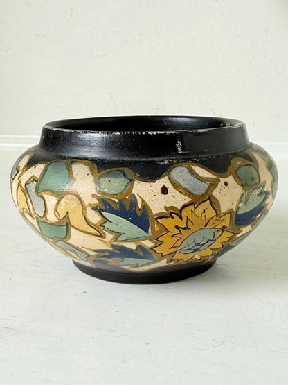 Brentleigh Ware Art Deco pottery jar with hand painted floral decoration on a black ground, photographed on a white surface