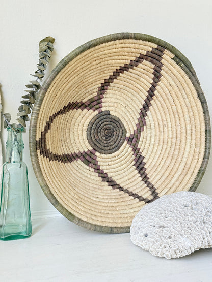 Large hand woven coiled basket with three point star pattern, natural fibre and dark geometric detail for wall or table styling