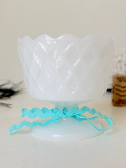 Vintage milk glass footed bowl with scalloped rim and pressed pattern, photographed on a white surface