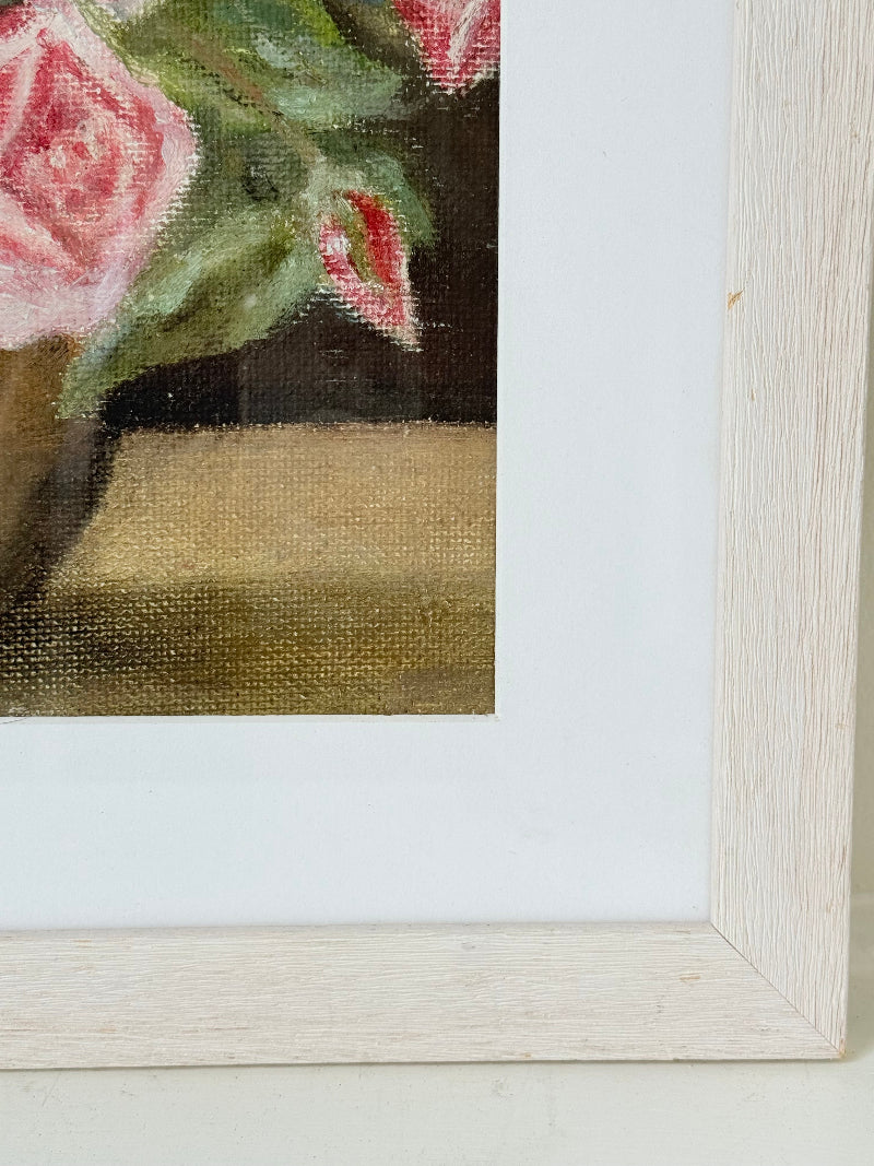 Framed original rose still life painting in pink and yellow, photographed on a white surface.