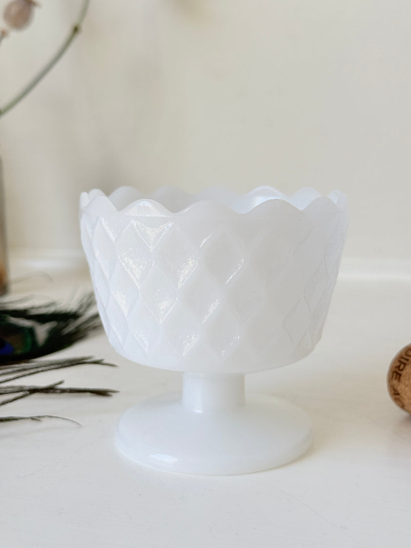 Vintage milk glass footed bowl with scalloped rim and pressed pattern, photographed on a white surface