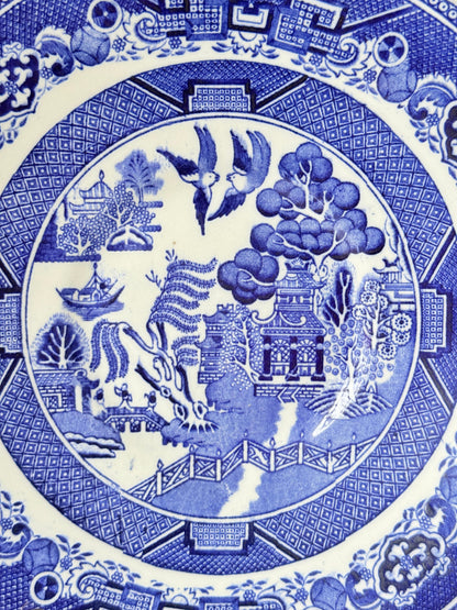 Blue Willow serving plate with cobalt blue transfer pattern shown on a white surface.