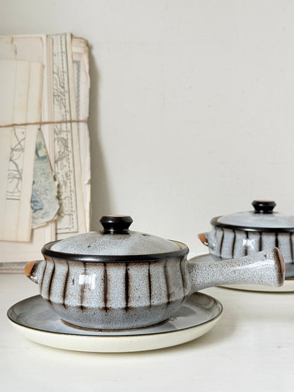 Denby Studio pair of lidded soup bowls with stands in grey and rust photographed on a white surface