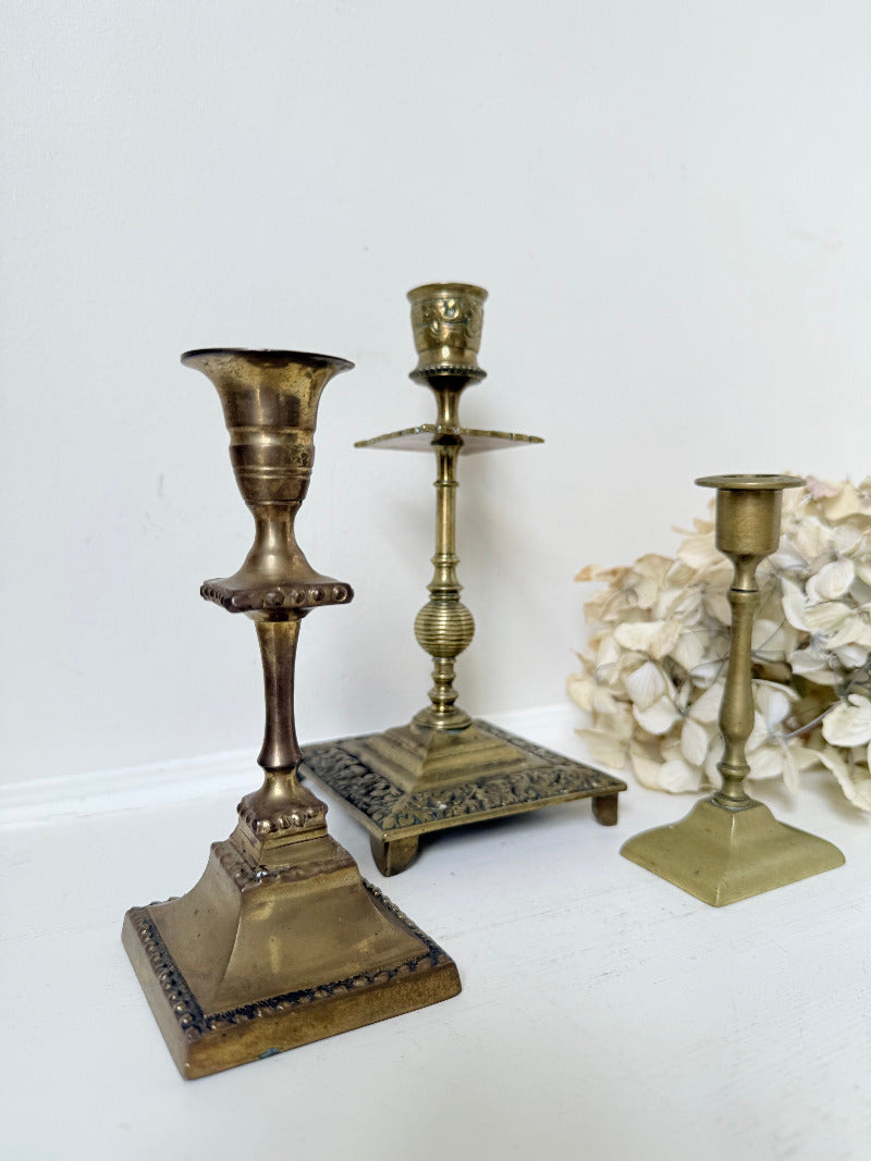 vintage brass trio of candlesticks in mixed designs photographed on white surface