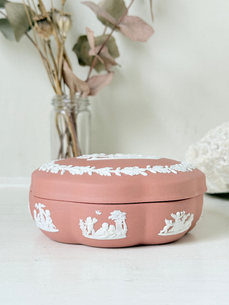 Rare vintage Wedgwood Jasperware round lidded trinket box in terracotta rose pink, with a central classical cameo scene and white laurel wreath border.