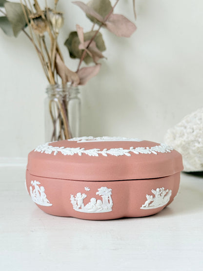 Rare vintage Wedgwood Jasperware round lidded trinket box in terracotta rose pink, with a central classical cameo scene and white laurel wreath border.