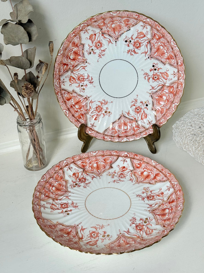 pair of vintage porcelain coral transfer plates with scalloped edges and gilt detail on white surface
