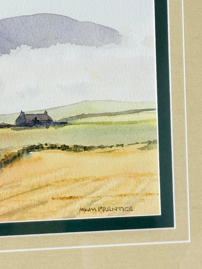 Framed Scottish watercolour coastal landscape by Martin W. M. Prentice in green frame with double mount, on white surface.