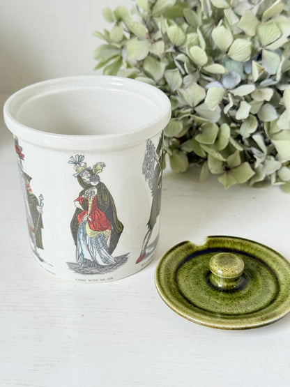 vintage Holkham pottery condiment pot with green lid and illustrated figures photographed on white surface
