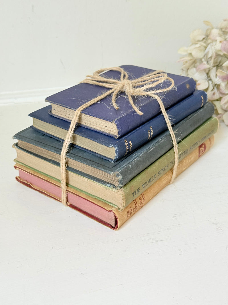 Vintage decorative book bundle in blue and green tied with twine, photographed on a white surface