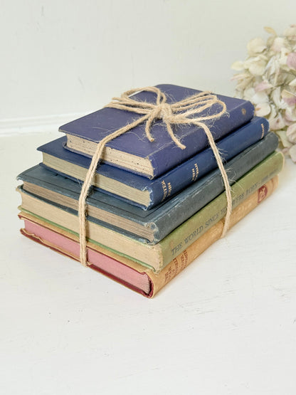 Vintage decorative book bundle in blue and green tied with twine, photographed on a white surface