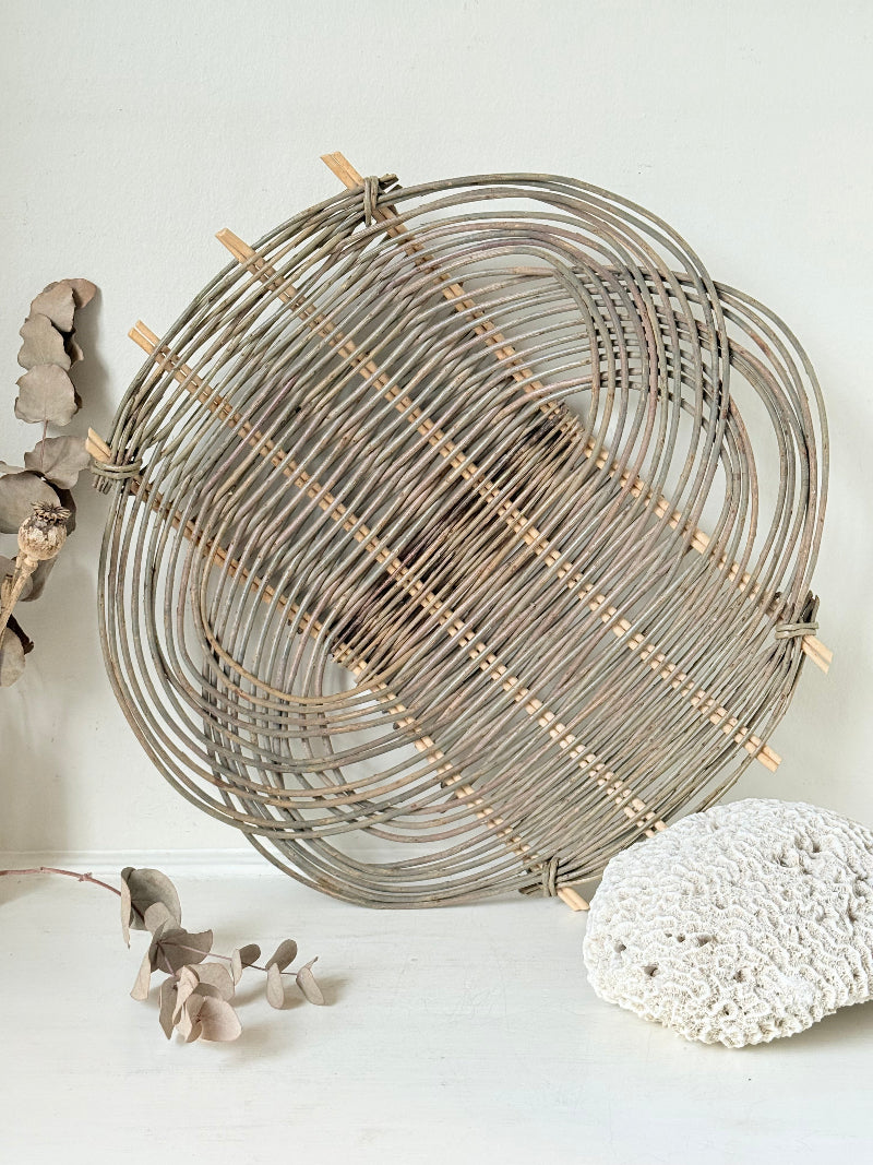 Large vintage loose weave rattan basket tray in grey tone, photographed on a white surface