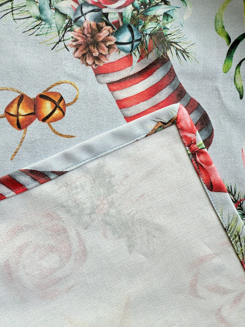 Blue Loft Christmas cotton tea towel with red striped stocking and festive motif pattern photographed on a white worktop.