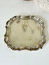 Vintage silver plate tray with scalloped edge and footed base, photographed on a white surface