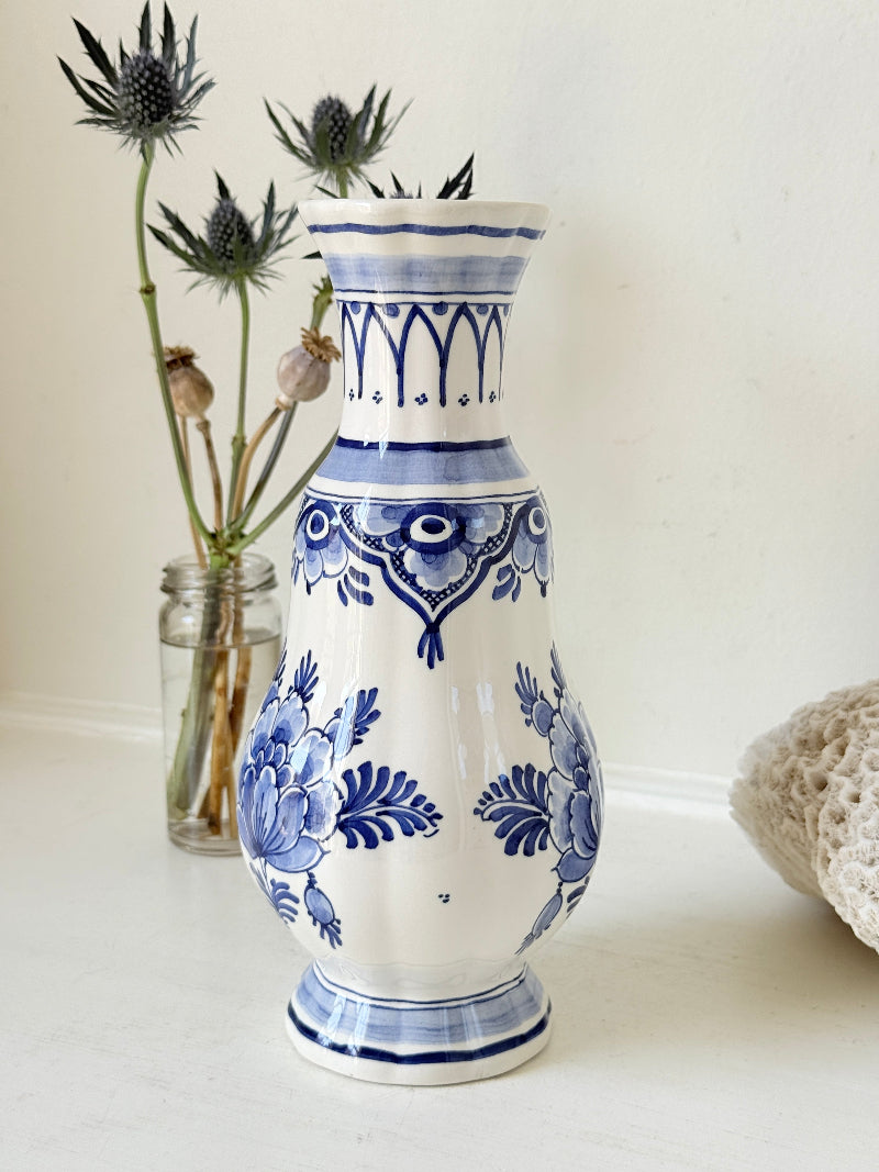 Vintage Delft style blue and white pottery vase with hand painted floral decoration, photographed on a white surface