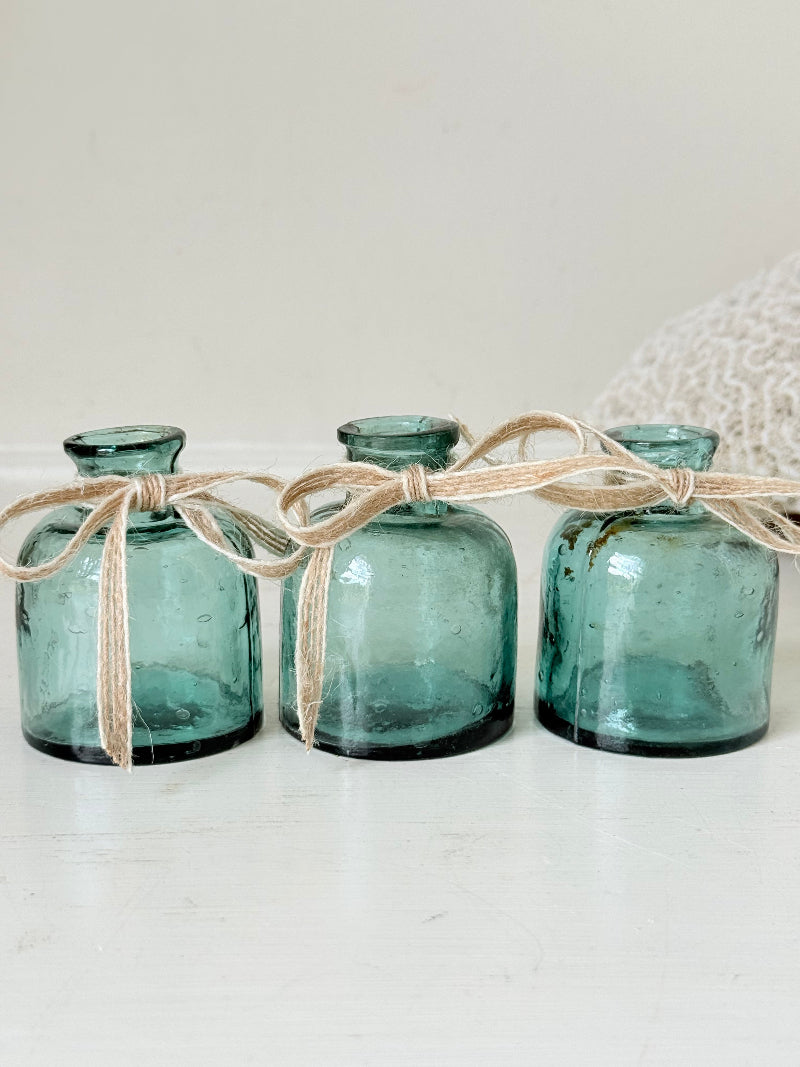 Set of antique green glass ink bottles with rounded forms, photographed on white surface.