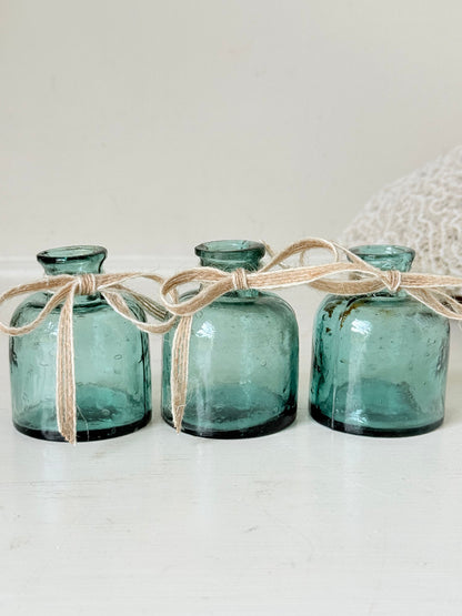 Set of antique green glass ink bottles with rounded forms, photographed on white surface.
