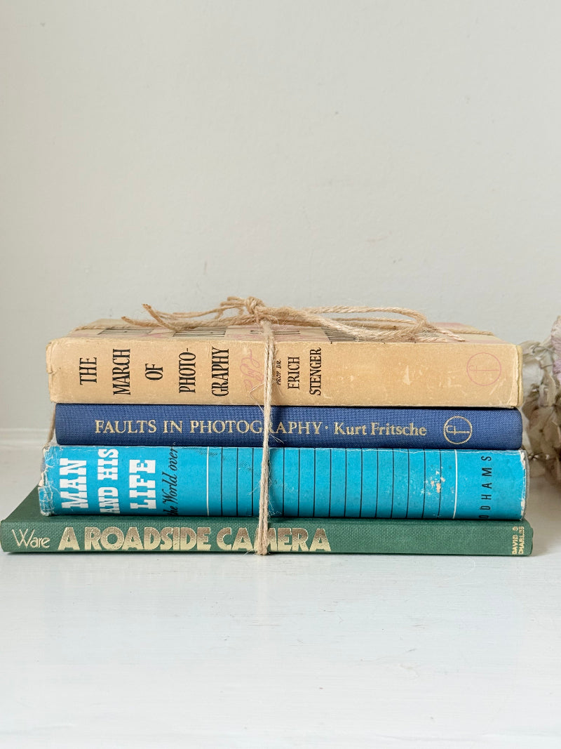 Bundle of vintage books in blue and neutral tones tied with twine, photographed on a white surface