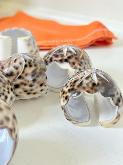 Set of eight vintage shell napkin rings with natural speckled patterning, photographed on a white surface