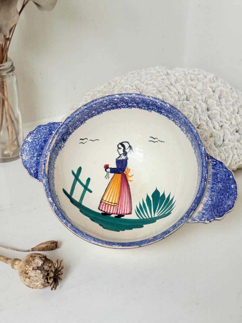Quimper faience olive bowl with Petit Breton figure and blue speckled rim photographed on a white surface