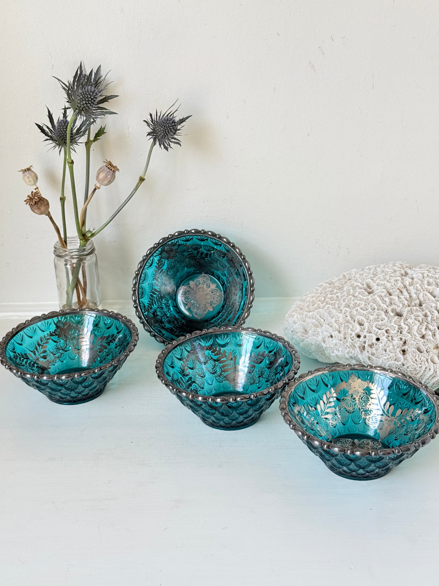 Set of four vintage teal pressed glass dessert bowls with gilt floral decoration, photographed on a white surface