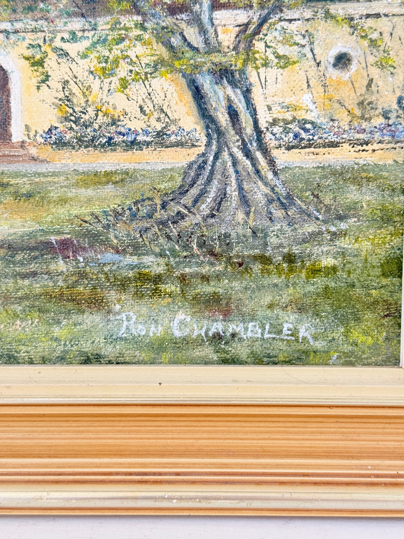 A close-up of a framed painting showing a tree trunk and grassy ground, with the signature &